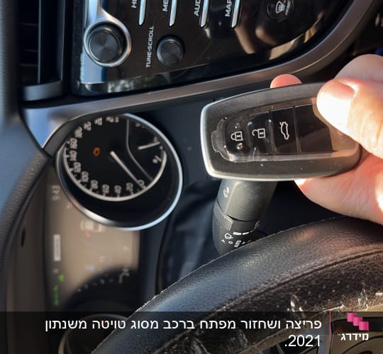 מפתח רכב מוחזק ביד מול לוח מחוונים
